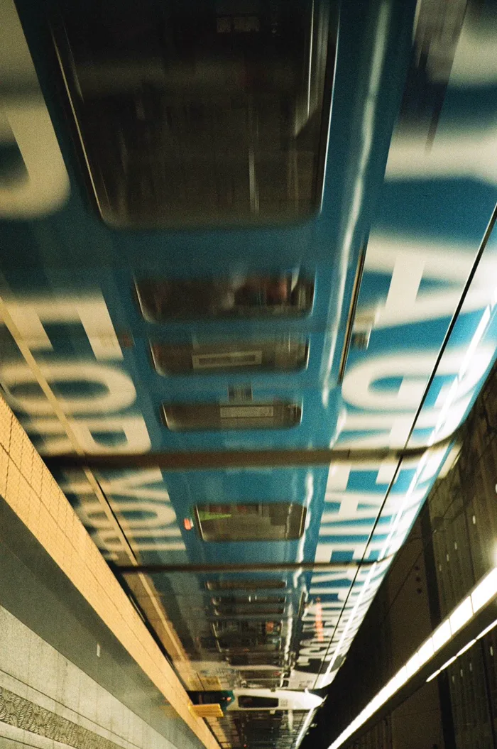 A blurred train speeding past an underground platform, turned sideways on the strip