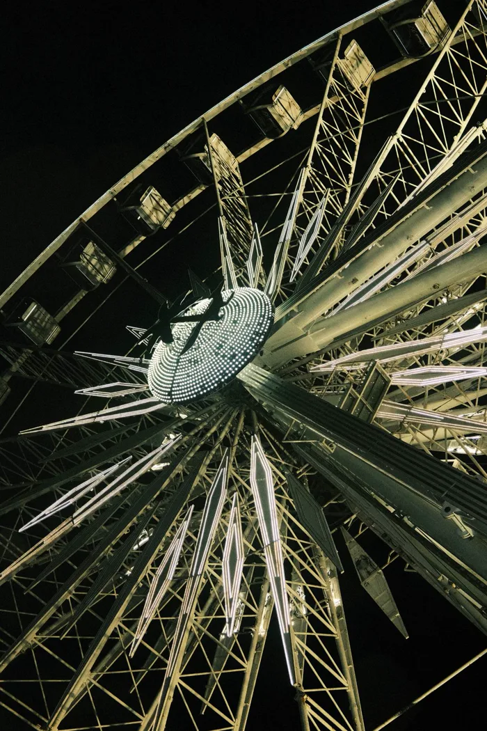 Looking up at a lit Ferris wheel at night